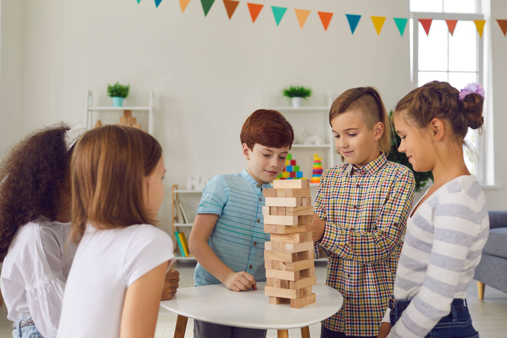 Groupe d'enfants divers jouant jeu de construction de tour de bloc de bois à la maison ou dans un club de loisirs - Photo, image