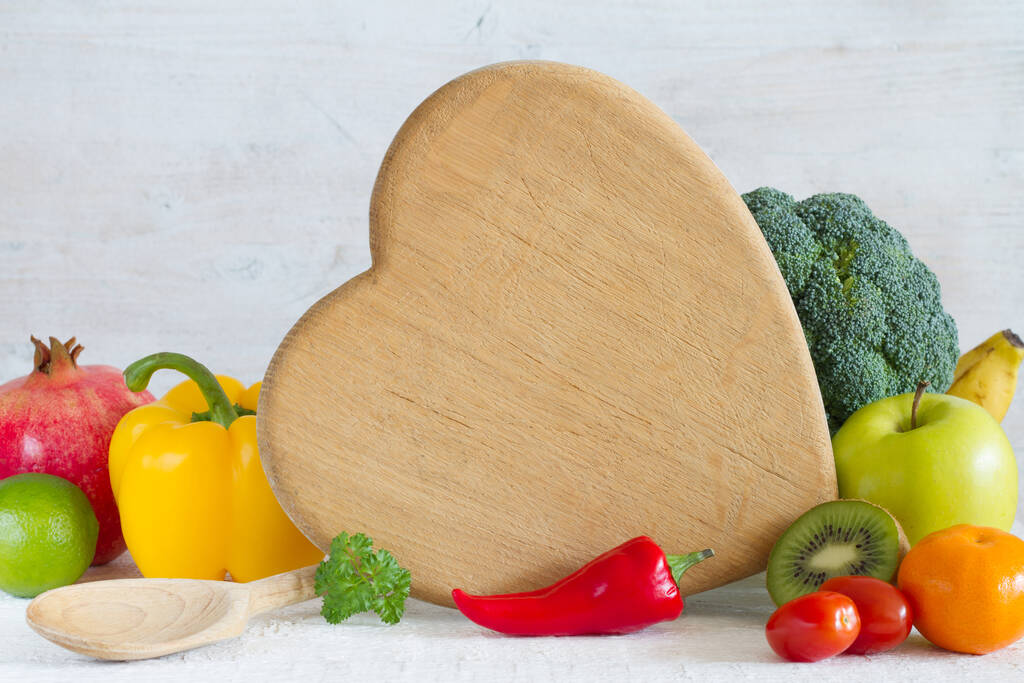 Tavola da cucina a forma di cuore, verdure, frutta e cucchiaio. Concetto di cibo sano - Foto, immagini