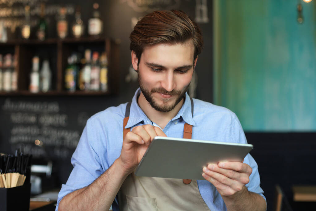 Giovane proprietario maschio utilizzando tablet digitale mentre in piedi in caffè - Foto, immagini