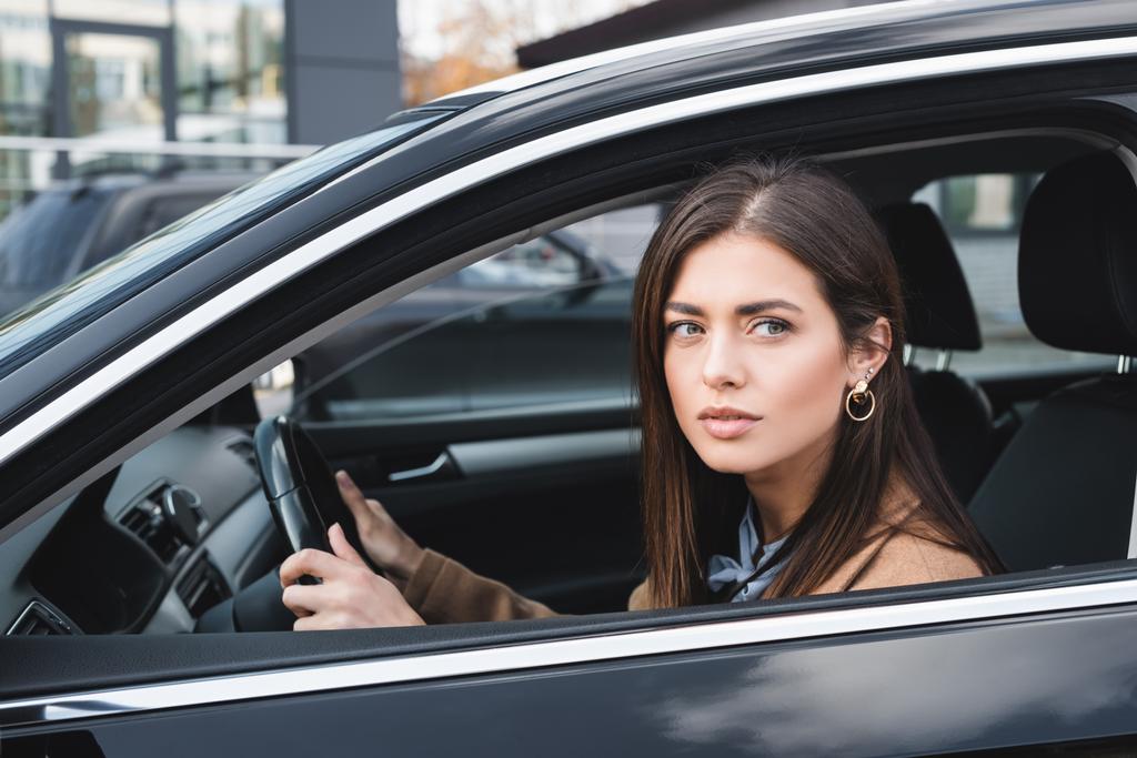 молода жінка дивиться з бічного вікна під час водіння автомобіля
 - Фото, зображення