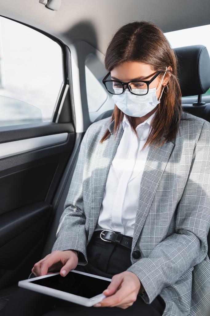 επιχειρηματίας σε γυαλιά ηλίου και ιατρική μάσκα χρησιμοποιώντας ψηφιακή ταμπλέτα στο αυτοκίνητο - Φωτογραφία, εικόνα