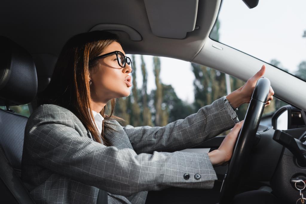 displeased businesswoman looking ahead and beeping while driving car - Photo, Image