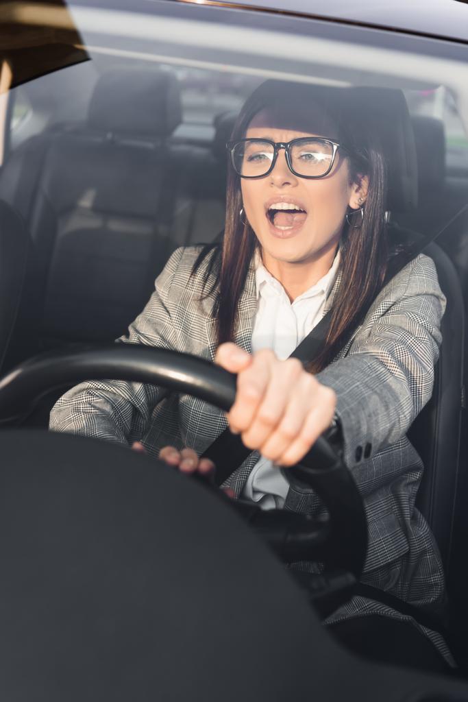 dühös nő sikoltozik és csipogó vezetés közben autó és előre néz elmosódott előtérben - Fotó, kép