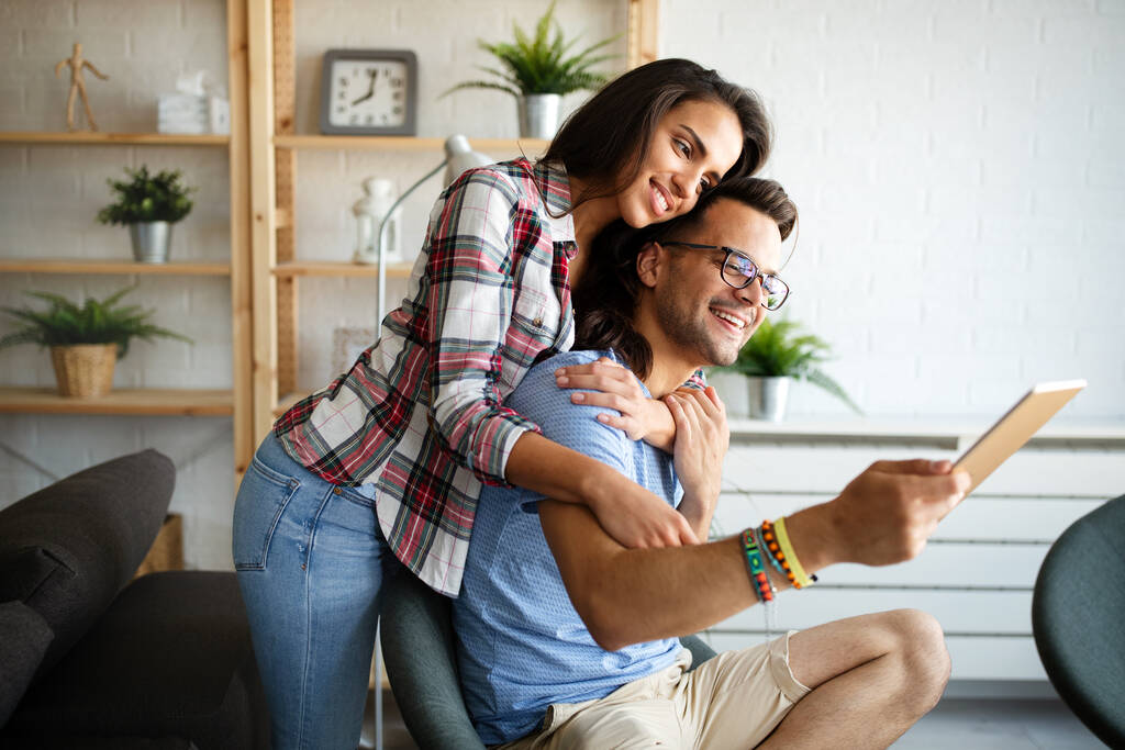 Пара влюбленных обнимает и использует планшет вместе дома - Фото, изображение