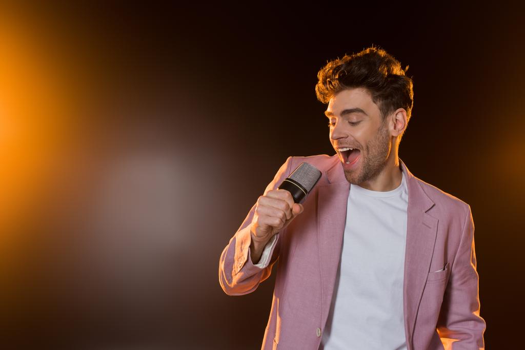 homem cantando enquanto segurando microfone no preto - Foto, Imagem