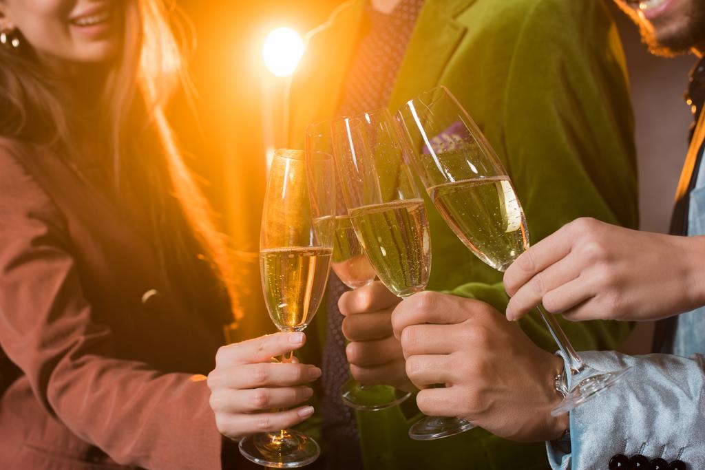 vista ritagliata di amici felici brindare bicchieri di champagne su nero  - Foto, immagini