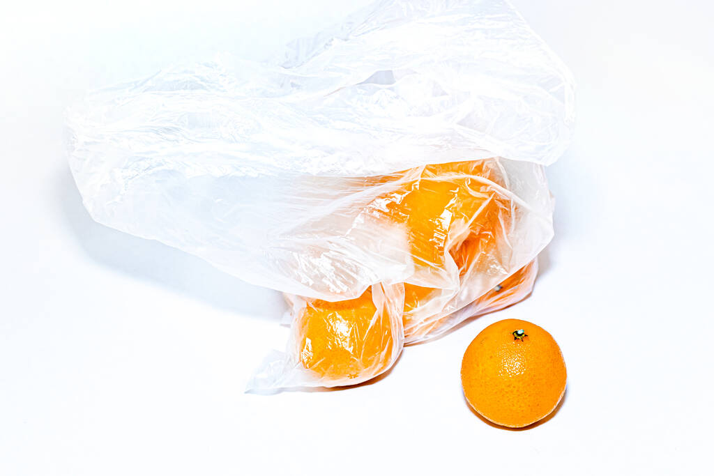 Mandarin and transparent cellophane plastic bag with ripe orange yellow tangerines on white background. Ecology concept.  - Photo, Image