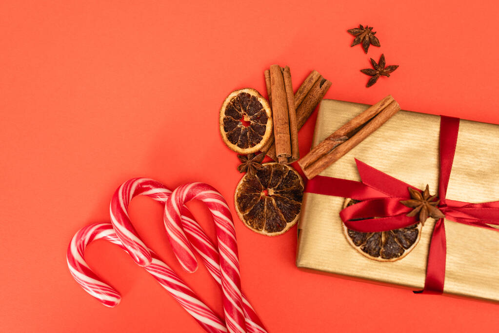 top view of gift with spices and candy canes on red background - Photo, Image