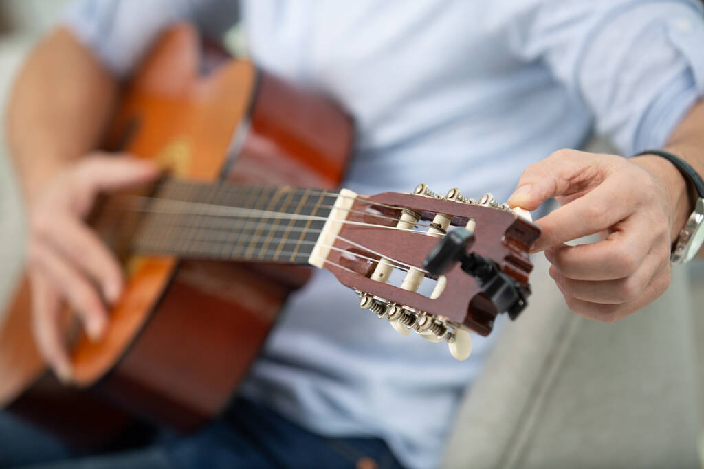 чоловічі руки налаштовують акустичну гітару
 - Фото, зображення