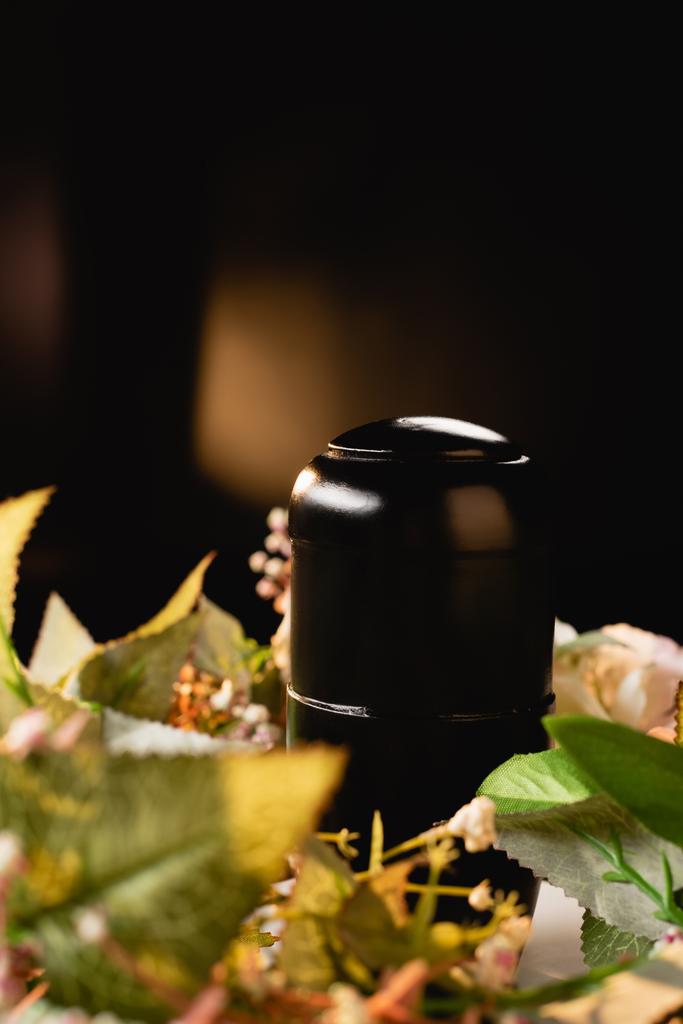 kukkakimppu ja uurna tuhkalla mustalla taustalla, hautajaiskonsepti - Valokuva, kuva