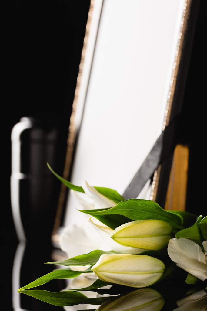 flowers, mirror with black ribbon and urn with ashes, blurred background - Photo, Image
