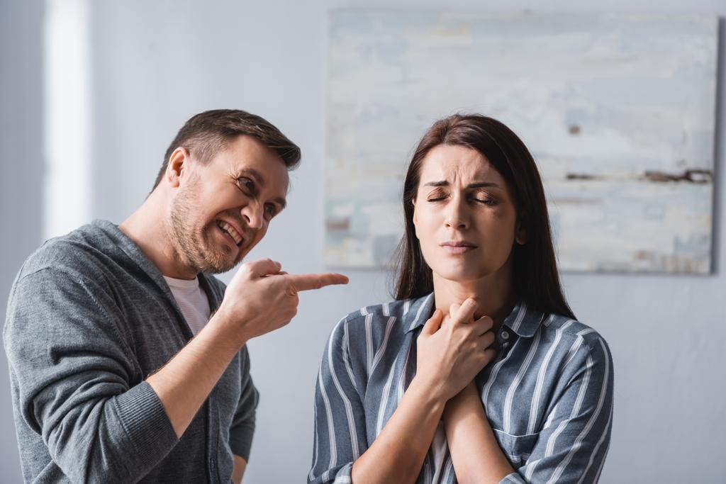 Vihainen mies osoittaa sormella järkyttynyt nainen mustelmia kotona  - Valokuva, kuva