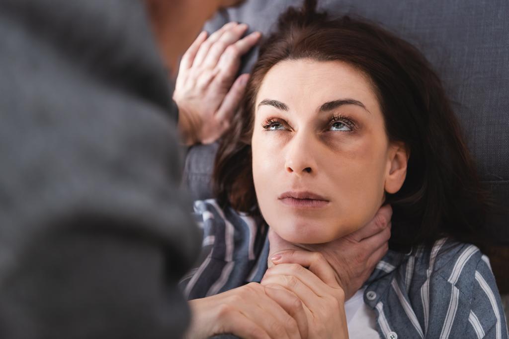 Mulher sufocante com hematomas no rosto perto do marido abusivo em primeiro plano desfocado  - Foto, Imagem