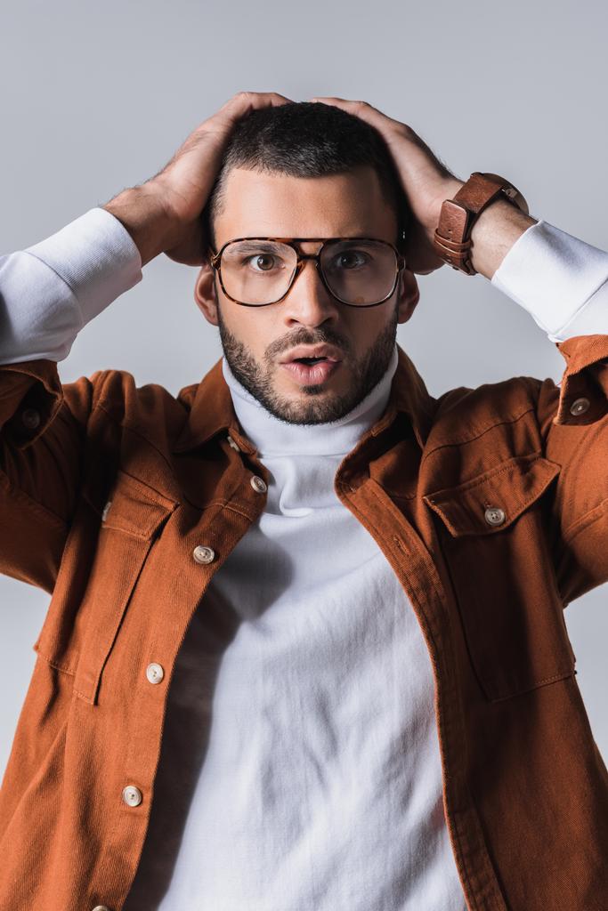 Emocionado hombre con estilo en gafas mirando a la cámara aislada en gris  - Foto, Imagen