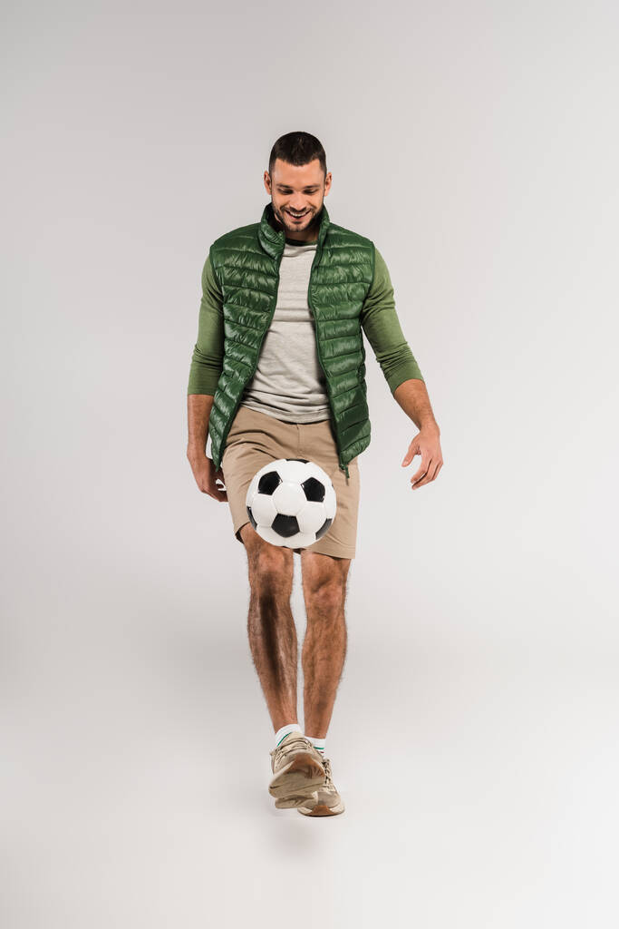 Wesoły sportowiec gra w piłkę nożną na szarym tle  - Zdjęcie, obraz
