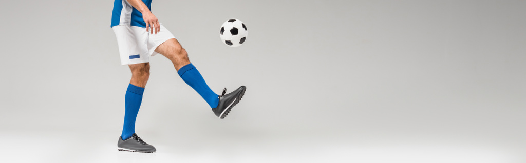 Обрізаний вид чоловіка, який грає у футбол на сірому фоні, банер
  - Фото, зображення