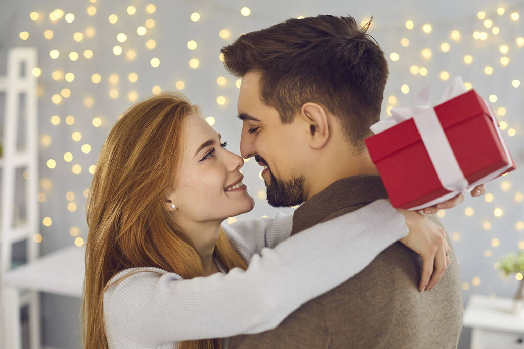 Young woman holding present box, embracing her boyfriend and thanking him for the gift - Photo, Image