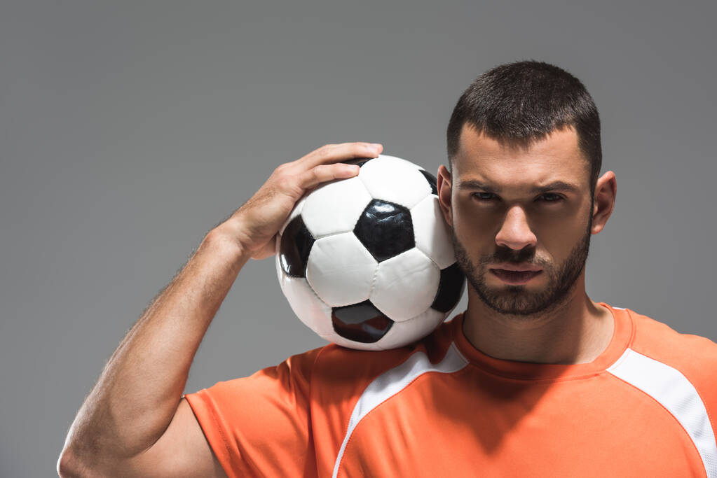 Szakállas sportoló kezében futball közel fej és nézi kamera elszigetelt szürke - Fotó, kép