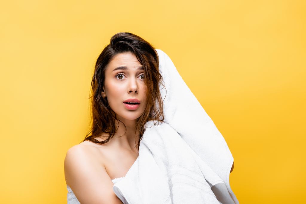 šokované krásná žena s mokrými vlasy a ručník izolované na žluté - Fotografie, Obrázek