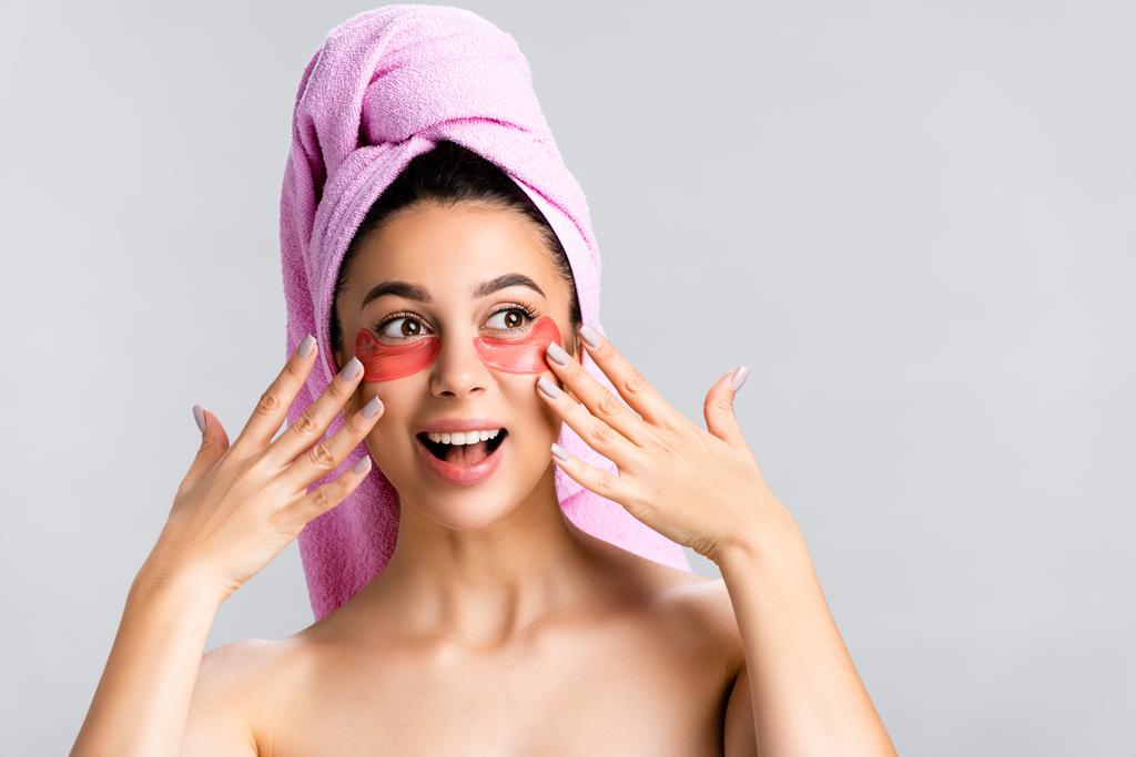 amazed beautiful woman with towel on hair and hydrogel eye patches on face isolated on grey - Photo, Image
