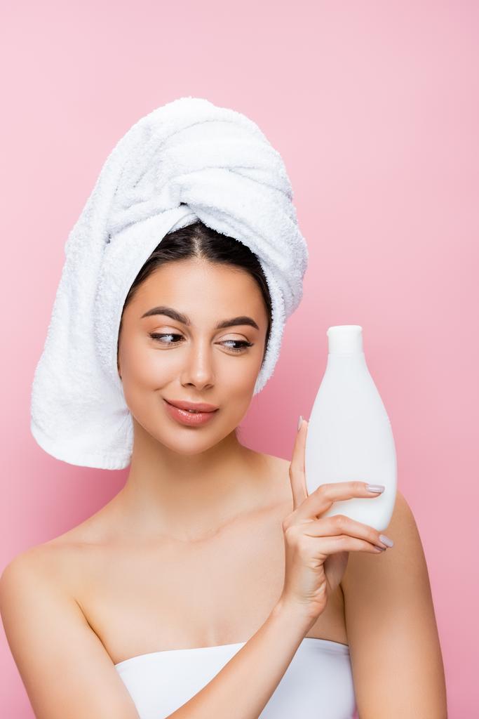 beautiful woman with towel on hair and bottle of lotion isolated on pink - Photo, Image