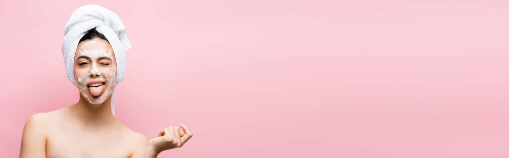 belle femme avec serviette sur cheveux et mousse sur le visage montrant la langue isolée sur rose, bannière - Photo, image