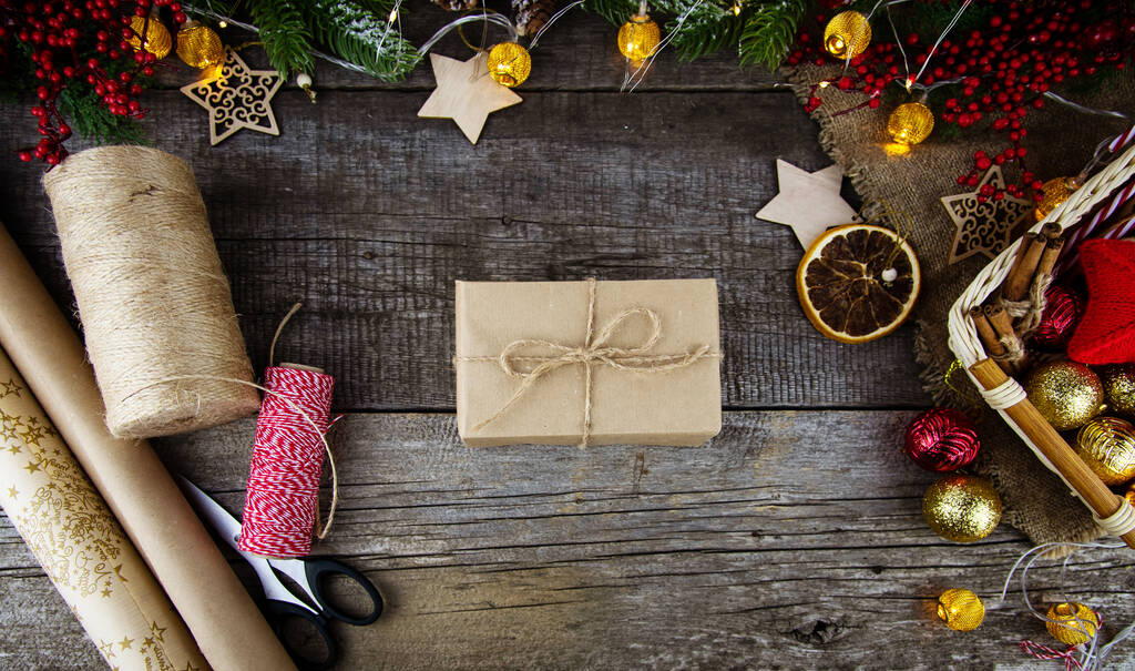 Plochý ležel obal vánočních dárků na dřevěném pozadí. Dárek, balicí papír, jutové lano, vánoční ozdoby. - Fotografie, Obrázek