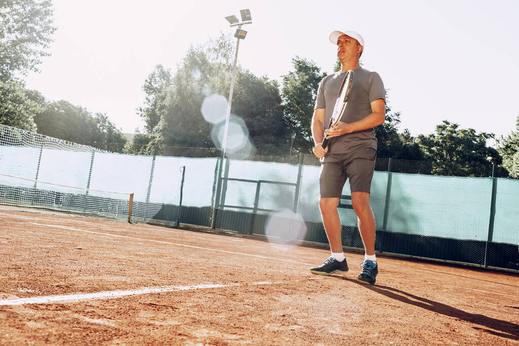 Μεσήλικας που παίζει τένις σε υπαίθριο τένις κατατίθεται - Φωτογραφία, εικόνα