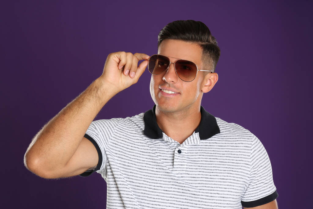 Schöner Mann mit Sonnenbrille auf lila Hintergrund - Foto, Bild