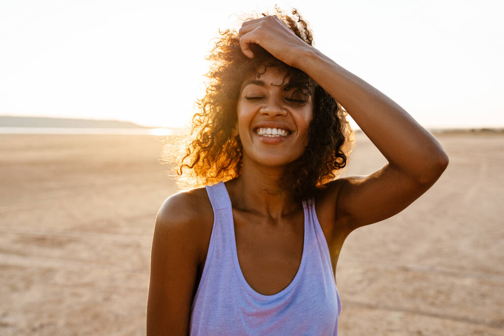 Kuva iloinen afrikkalainen amerikkalainen nainen hymyilee kameran edessä poseeratessaan autiomaassa - Valokuva, kuva