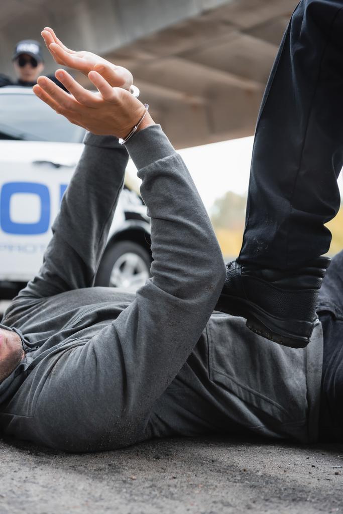 policista šlápnutí na odevzdané pachatel ležící na ulici na rozmazaném pozadí - Fotografie, Obrázek