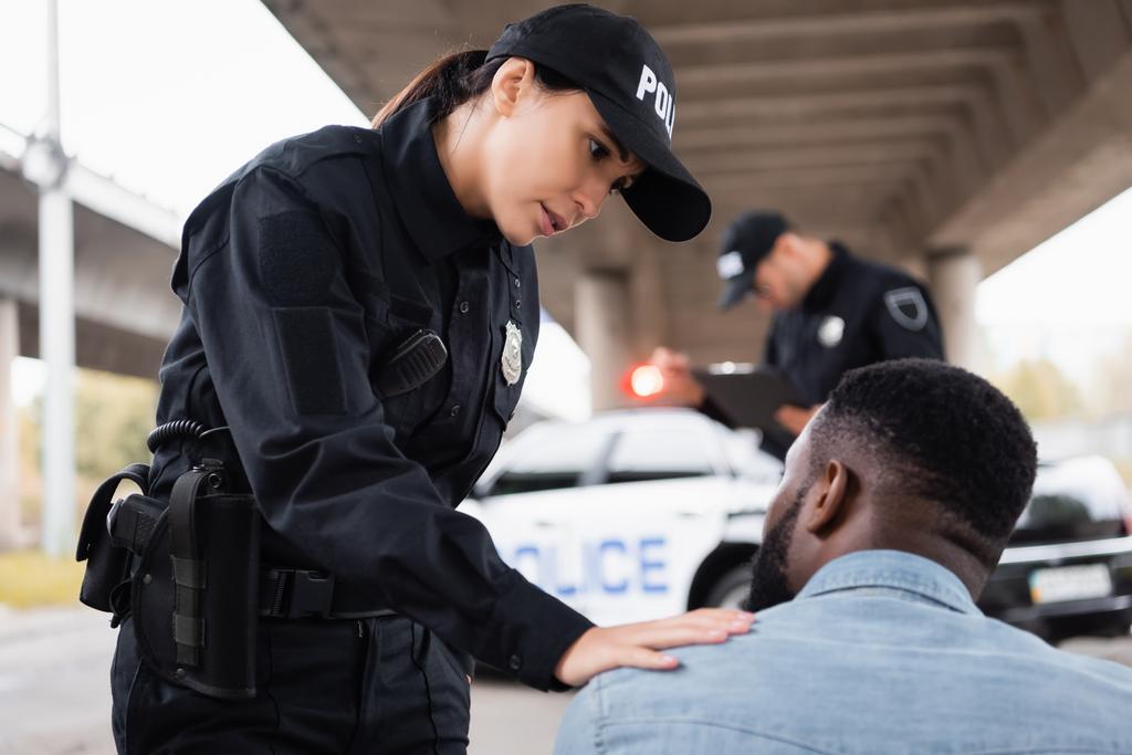 Policial calmante afro-americano homem perto colega em fundo borrado na rua urbana  - Foto, Imagem