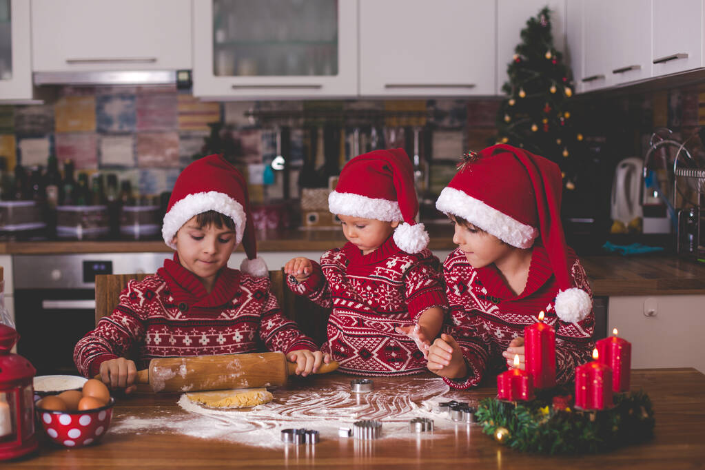 Süßes Kleinkind und sein älterer Bruder, Jungs, helfen Mama bei der Zubereitung von Weihnachtsplätzchen zu Hause in der Küche - Foto, Bild
