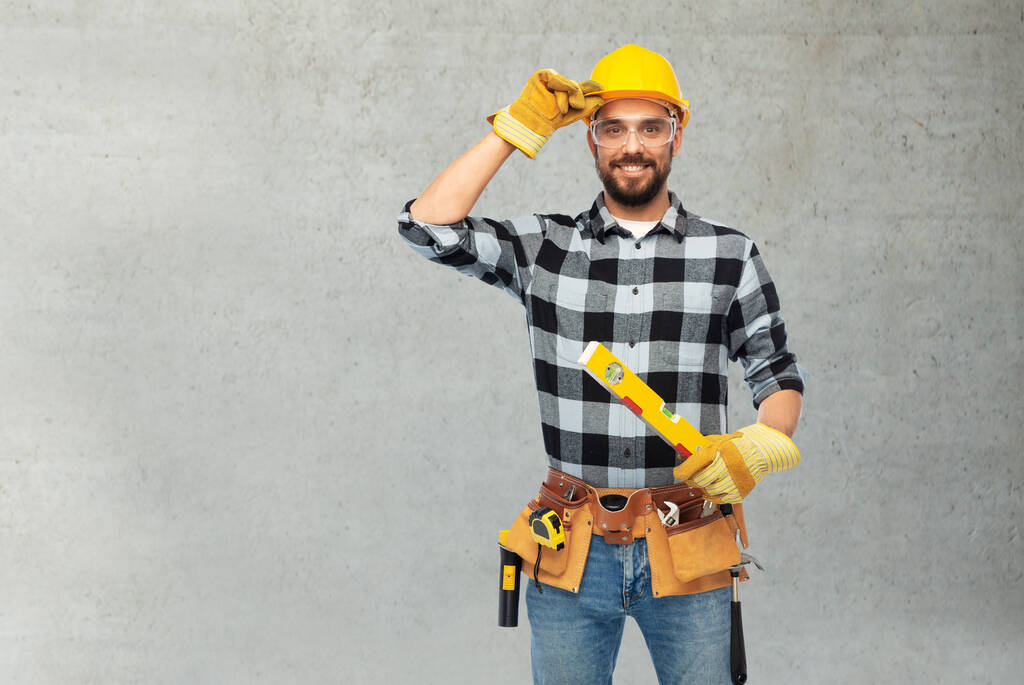 feliz trabajador masculino o constructor en casco con nivel - Foto, imagen