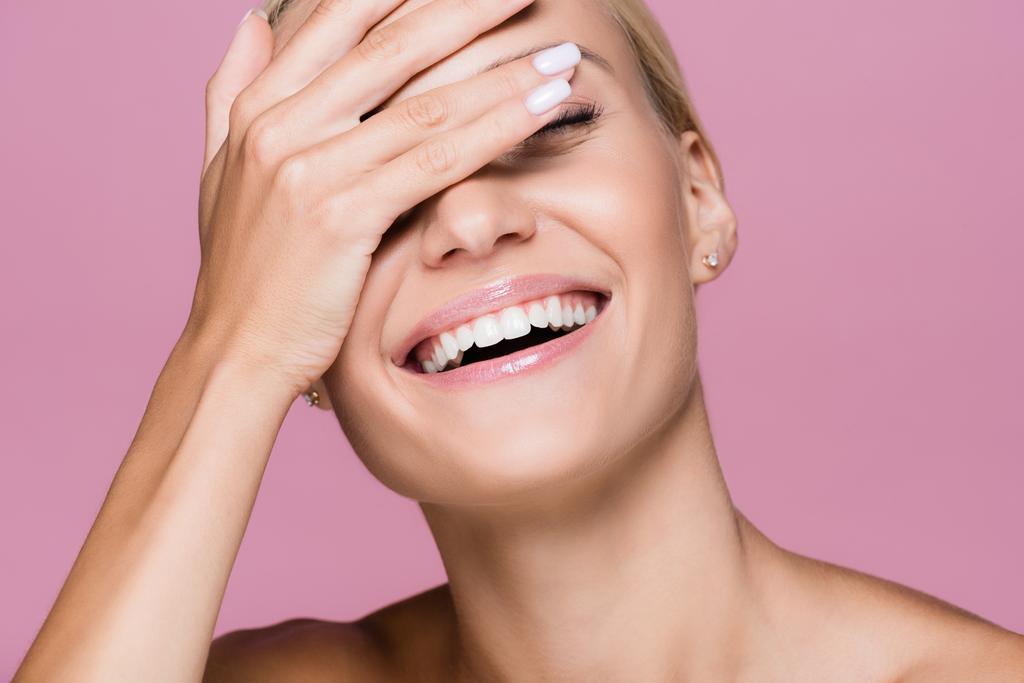 lächelnd schöne blonde Frau posiert mit der Hand auf dem Gesicht isoliert auf rosa - Foto, Bild
