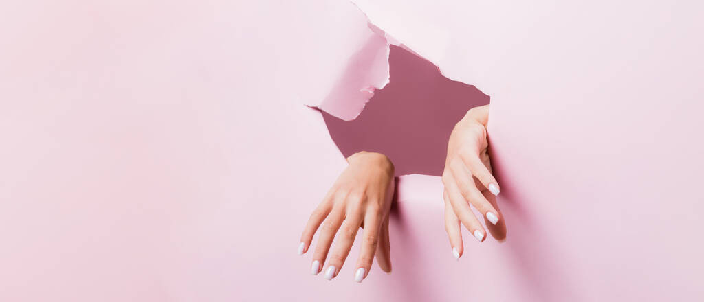 przycięty widok żeńskich rąk w różowym papierowym otworze - Zdjęcie, obraz