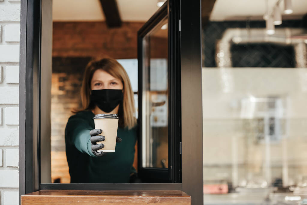 Barista mascherato versa il caffè dalla finestra a causa di coronavirus - Foto, immagini