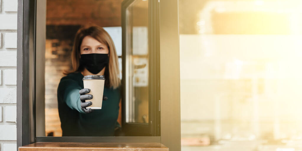マスク・バリスタはコロナウイルスのために窓からコーヒーをこぼす - 写真・画像