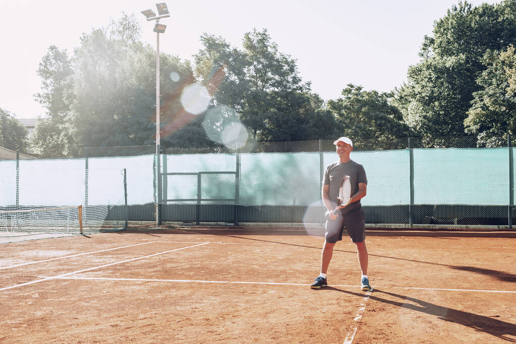 Middle-aged man playing tennis on outdoor tennis filed - Photo, Image