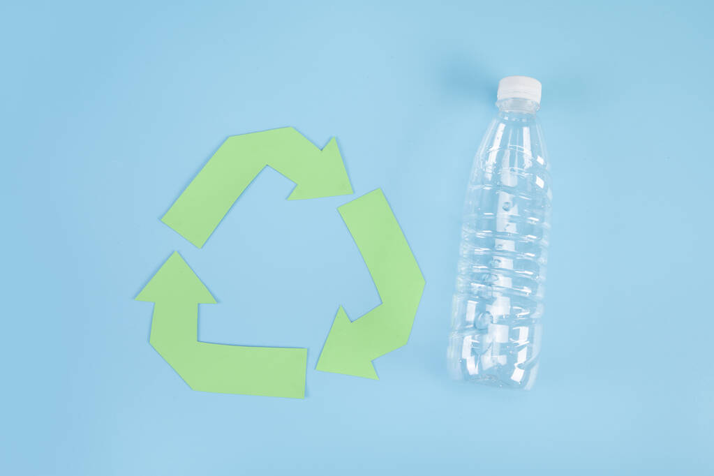 Bovenaanzicht van plastic fles en recyclingbord op blauw oppervlak, recyclingconcept - Foto, afbeelding