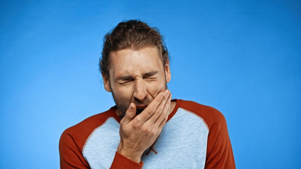 втомлений чоловік позіхає і прикриває рот на синьому
 - Фото, зображення