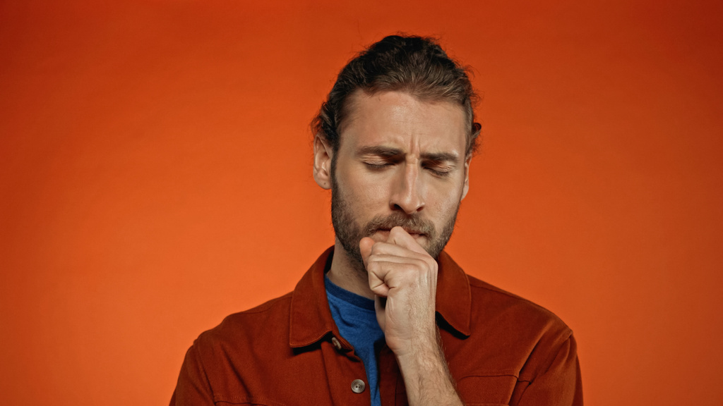 fiatal szakállas férfi gondolkodás narancs háttér  - Fotó, kép