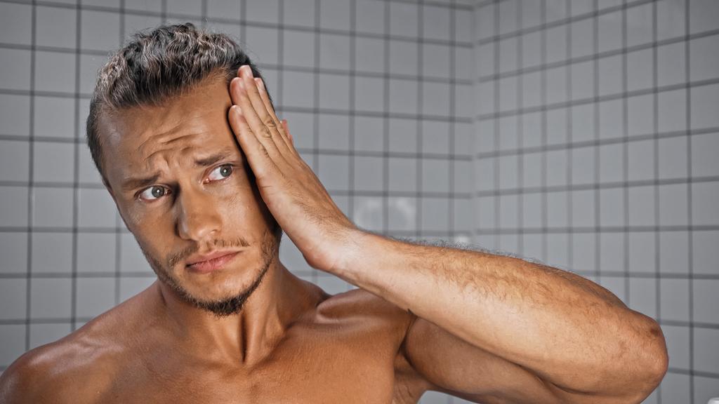 Üstsüz genç adam banyoda saç düzeltiyor.  - Fotoğraf, Görsel