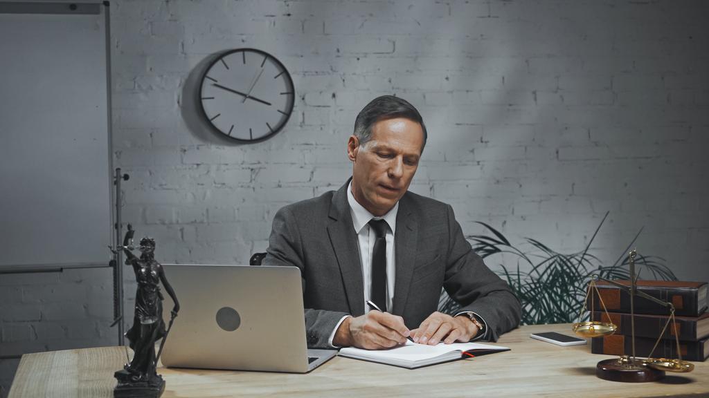 Страховой агент пишет на ноутбуке во время работы рядом с устройствами и весами  - Фото, изображение