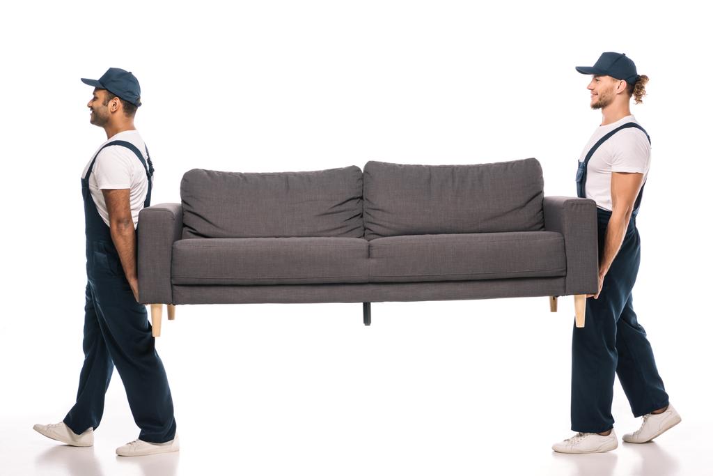 teljes hossza vidám multikulturális mozgó cipelő kanapé és séta fehér  - Fotó, kép