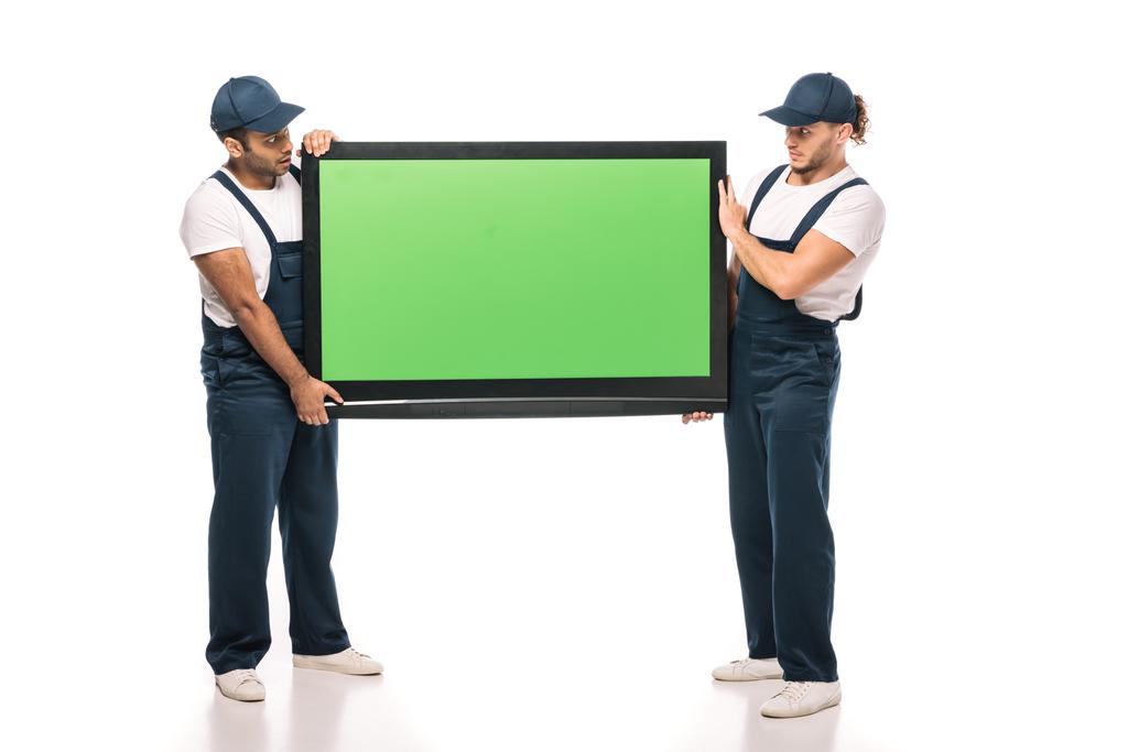 volle Länge der überraschten multikulturellen Macher tragen Plasma-TV mit grünem Bildschirm auf weißem Hintergrund - Foto, Bild