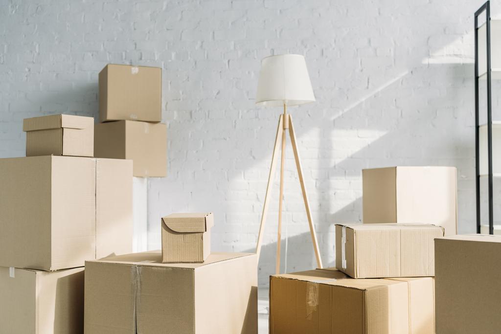pila de cajas de cartón cerca de lámpara de pie en apartamento moderno  - Foto, imagen