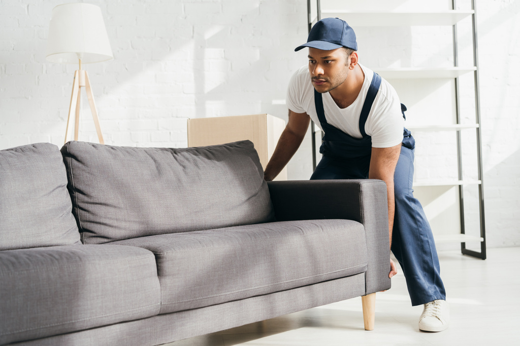 Indiano mover em uniforme e cap carregando sofá no apartamento  - Foto, Imagem