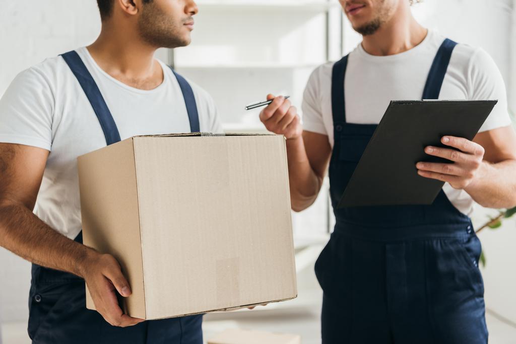 cropped view of multicultural movers holding boxes in apartment  - Photo, Image