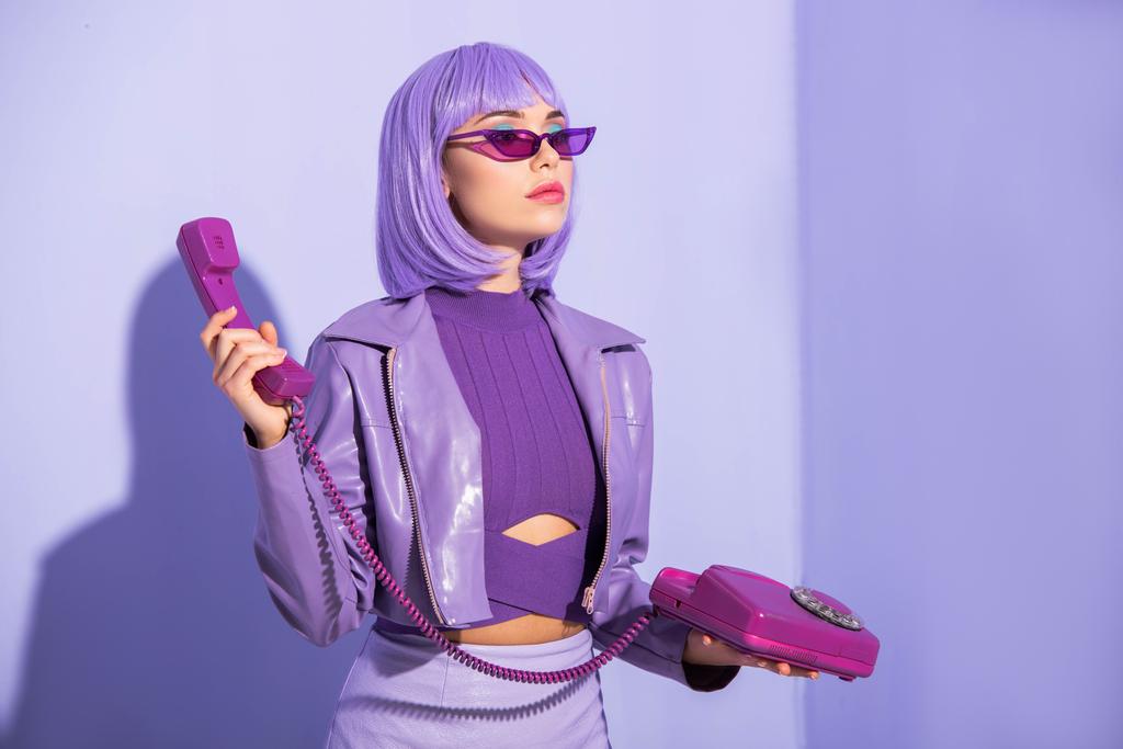 mujer joven vestida con estilo de muñeca con teléfono retro sobre fondo de color violeta - Foto, imagen